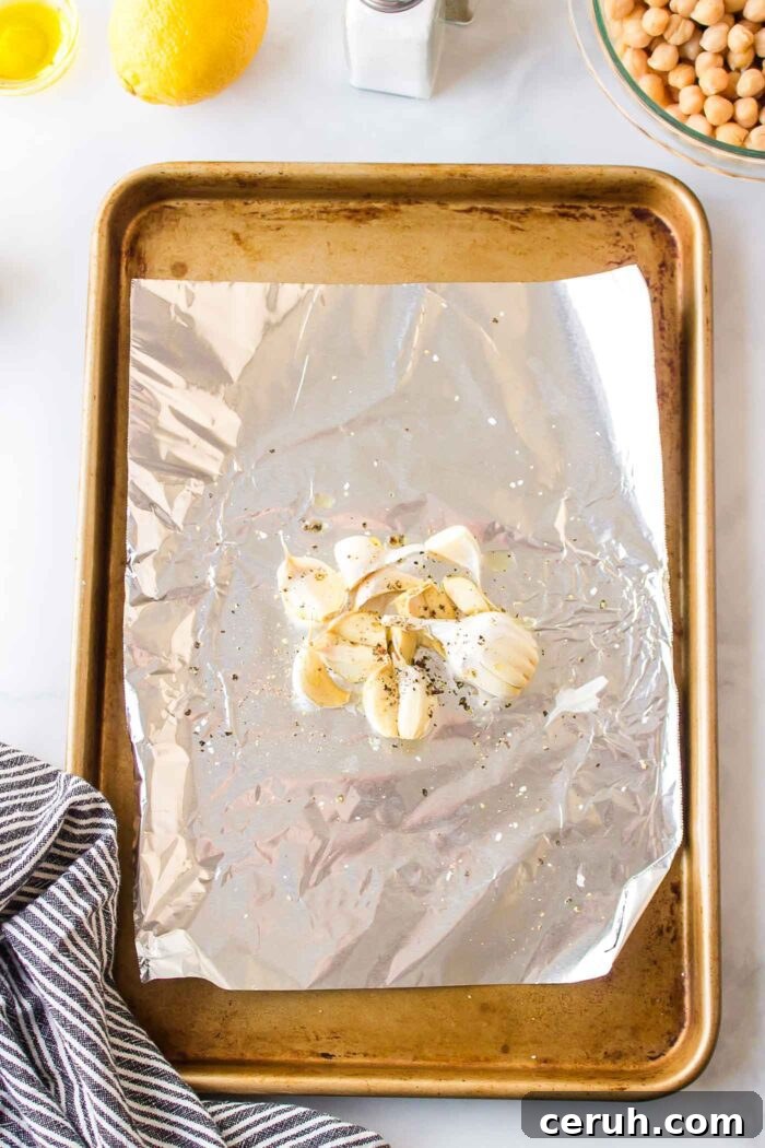 Whole cloves of garlic on a piece of foil on a roasting tray.