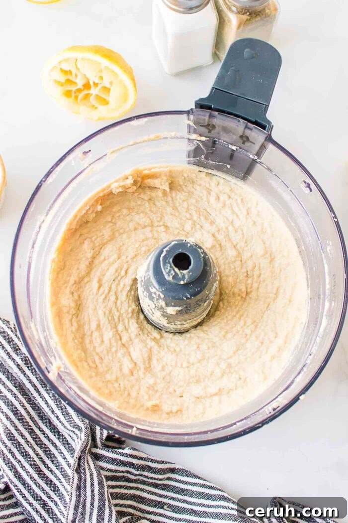 Smooth and creamy hummus in a food processor container.