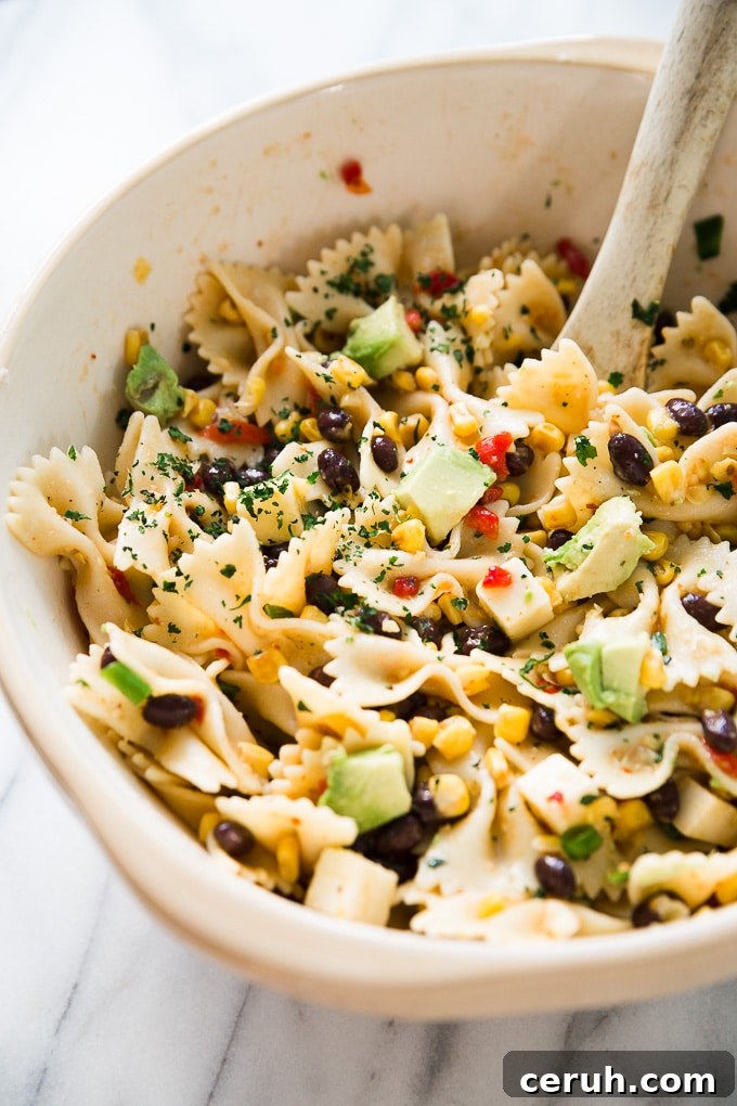 Southwest Pasta Salad embraces the sweetness of cream style corn and the smokiness of chipotle sauce, perfect for warm weather. Southwest Pasta Salad in a bowl on a counter top.