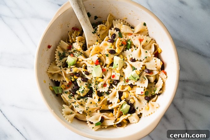 Southwest Pasta Salad: sweet cream-style corn with smoky chipotle for a refreshing summer side. Southwest Pasta Salad with wooden spoon.