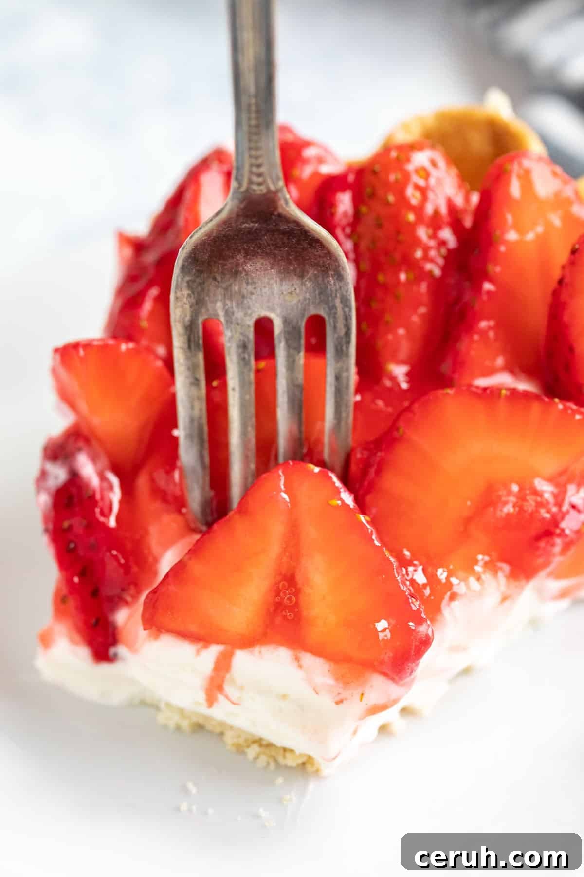 A close up image of a fork piercing into the strawberry pie with cream cheese.