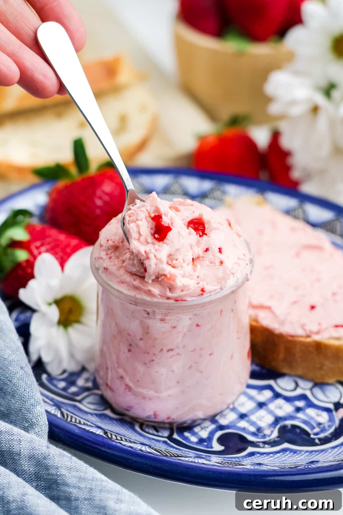 Strawberry butter in a jar on a white and blue plate. 