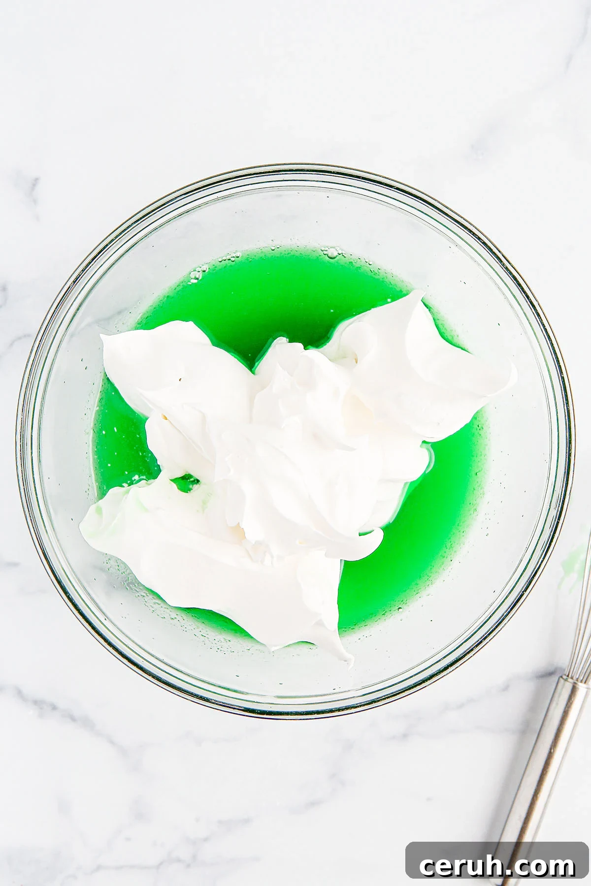 Cool whip added to lime gelatin and water in the mixing bowl.