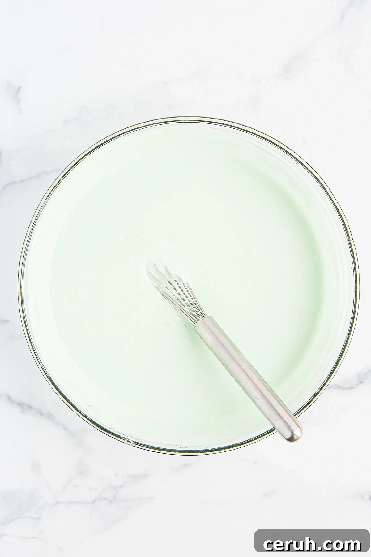 Lime gelatin and cool whip whisked together in a mixing bowl.