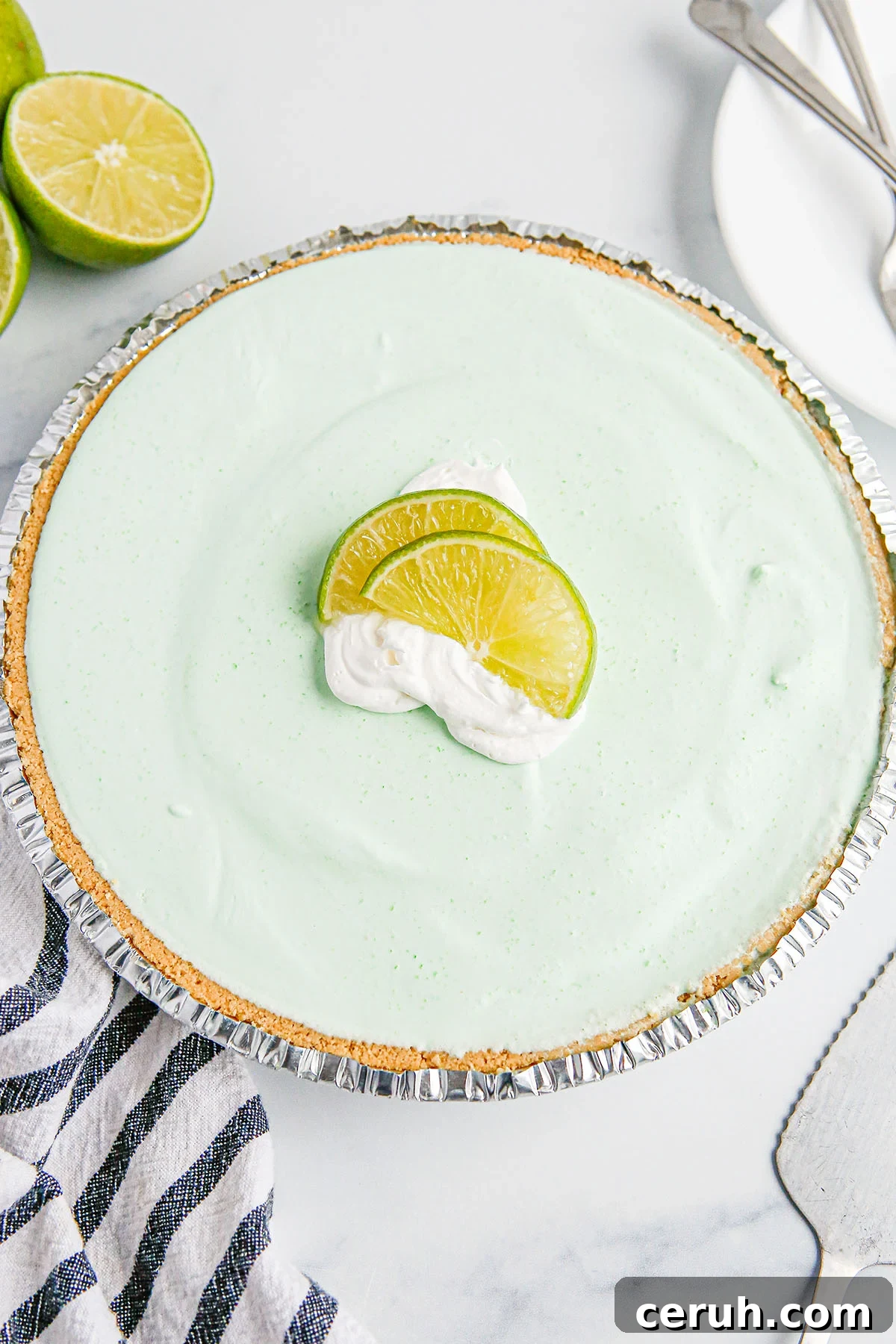 Lime Pie in graham cracker crust topped with whipped cream and lime slices.