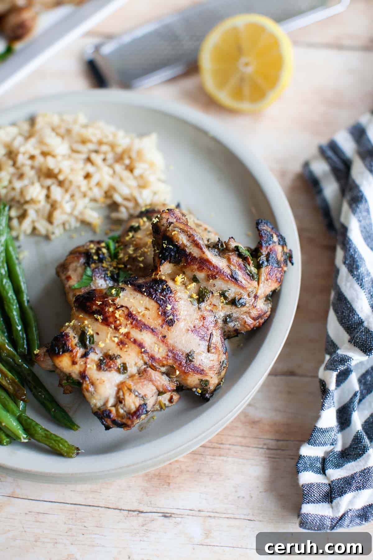a gray plate with rice, lemon marinated chicken, and green beans.