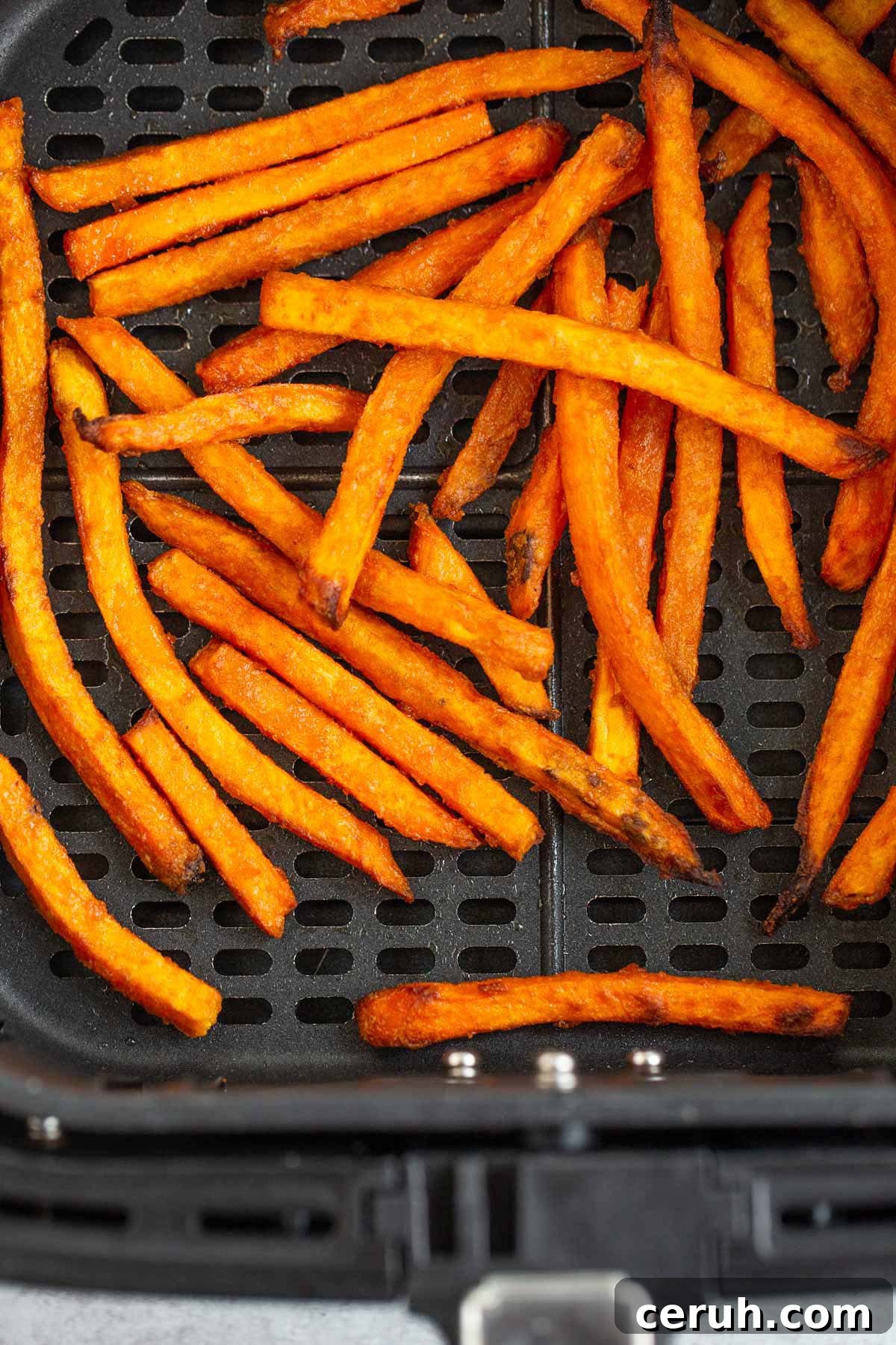 Cooked sweet potato fries in air fryer basket.