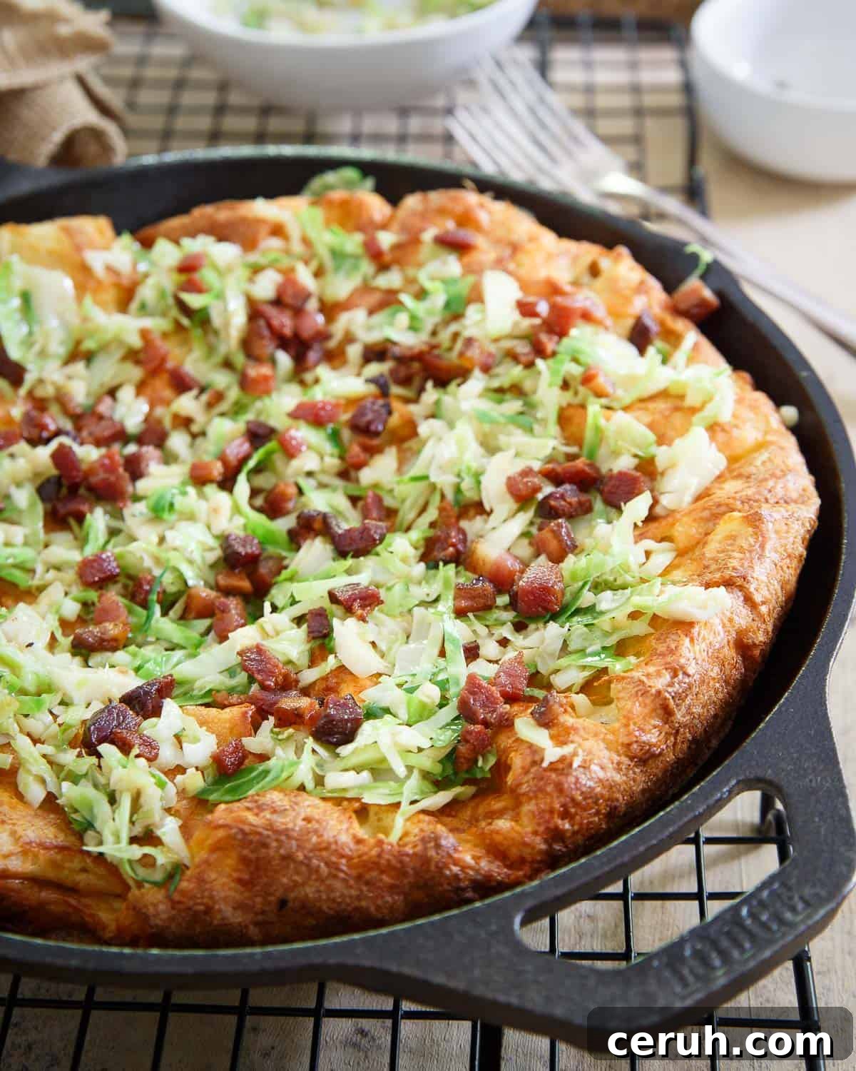 This cheddar Dutch baby is topped with crispy bacon and sautéed brussels sprouts for a savory take on the classic Dutch pancake.