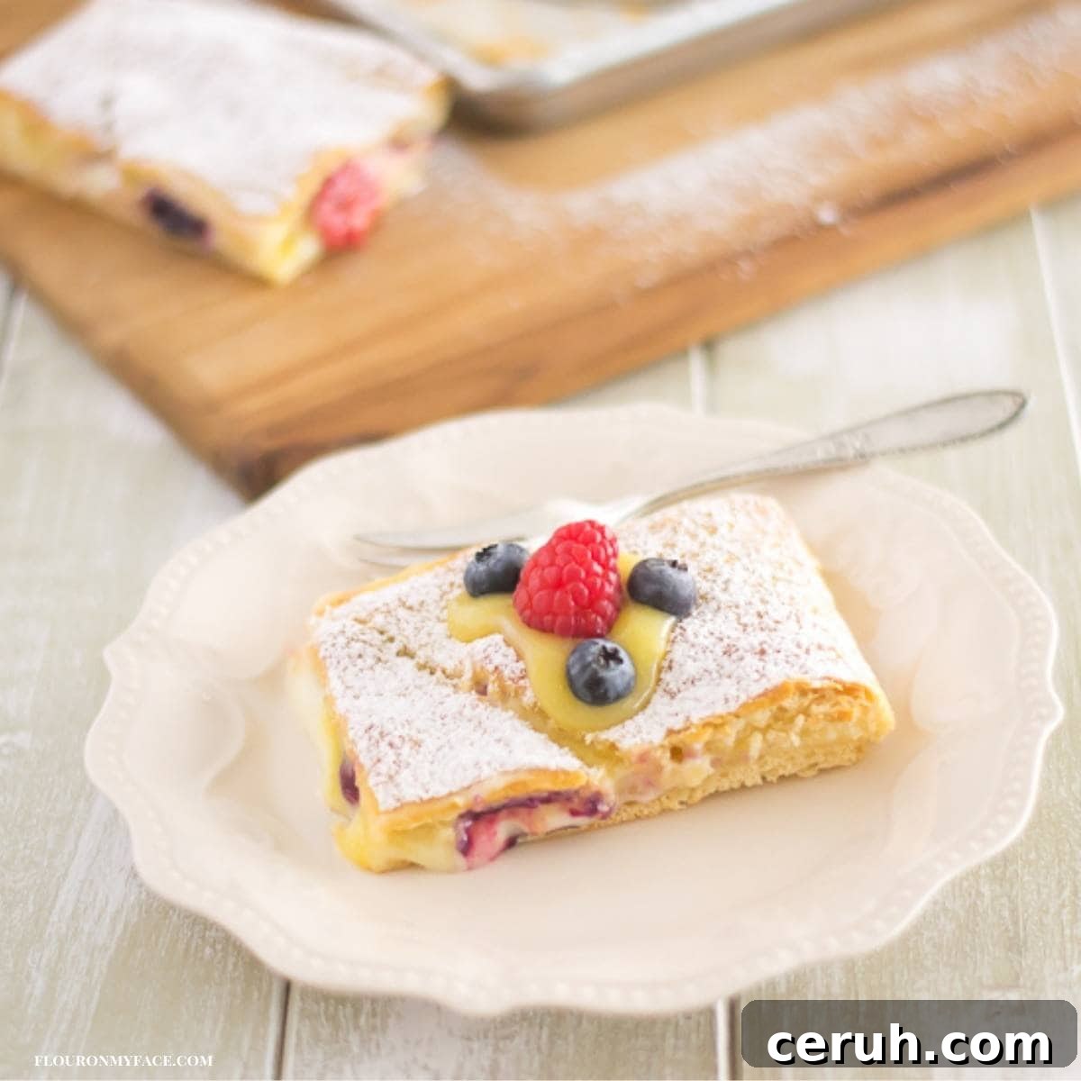 A lemon curd filled crescent bar topped with berries on a plate.