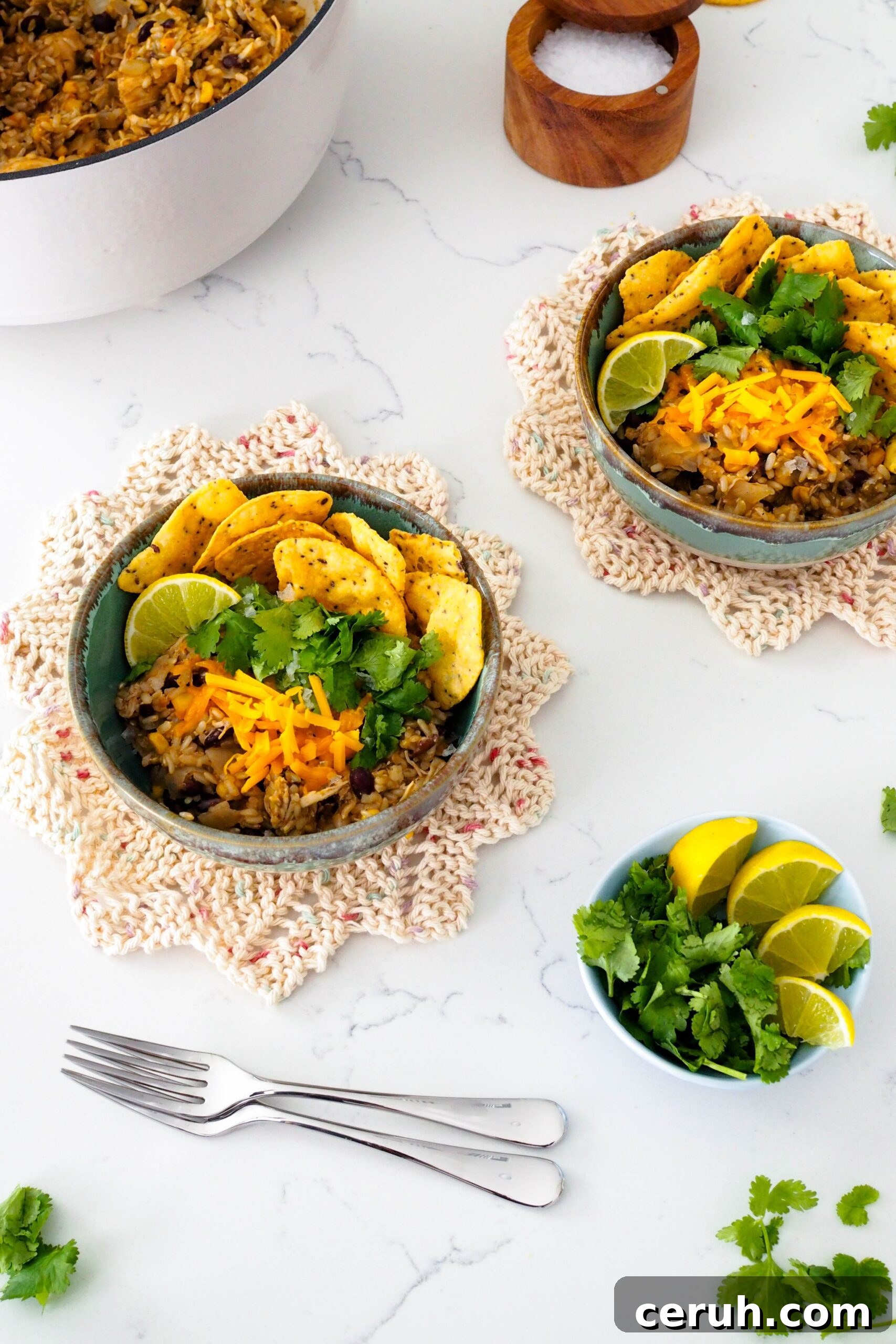 Two bowls of one-pot chicken and brown rice with various toppings.