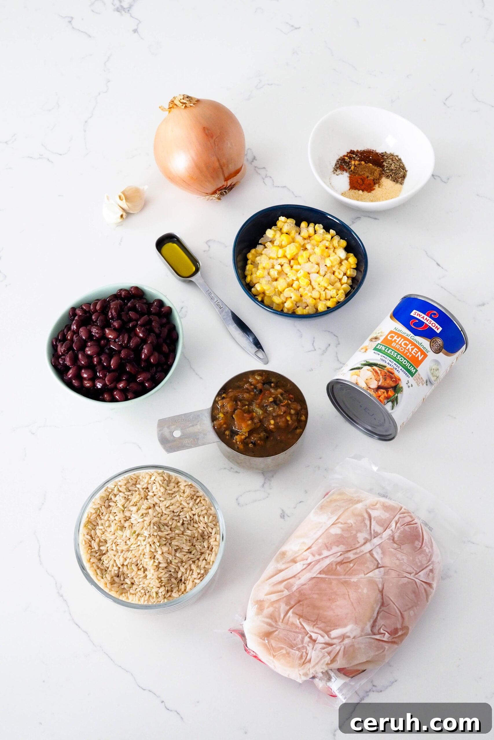 The ingredients for one-pot chicken and brown rice on a quartz countertop.