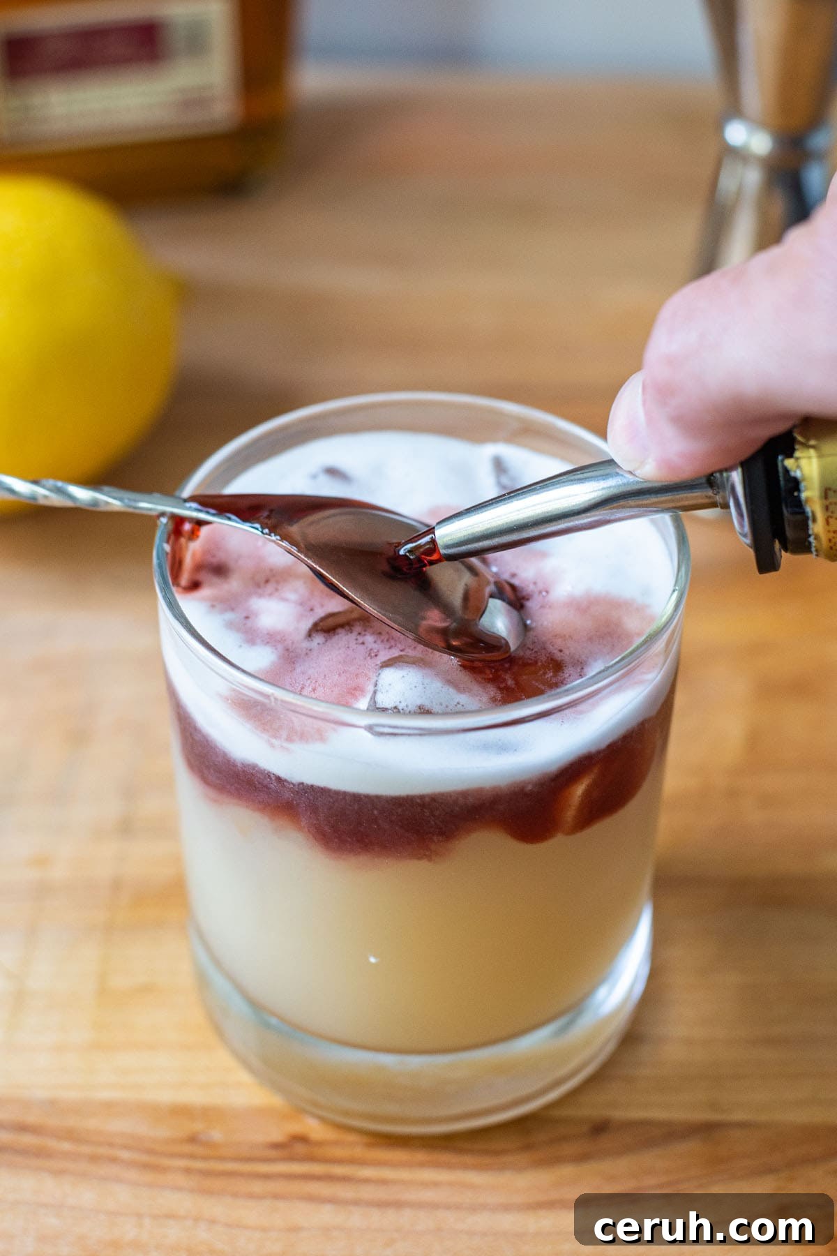 Pouring a red wine float over a bar spoon in a New York Sour.