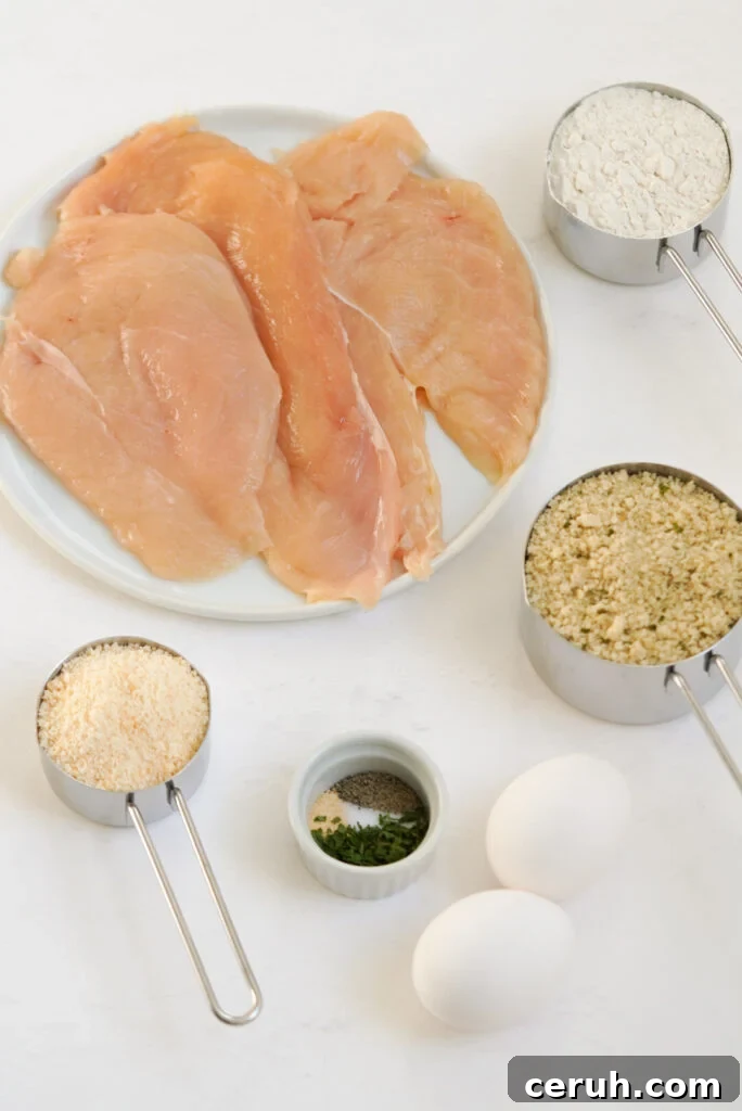 ingredients needed to make breaded baked chicken cutlets measured out into bowls on a white table.