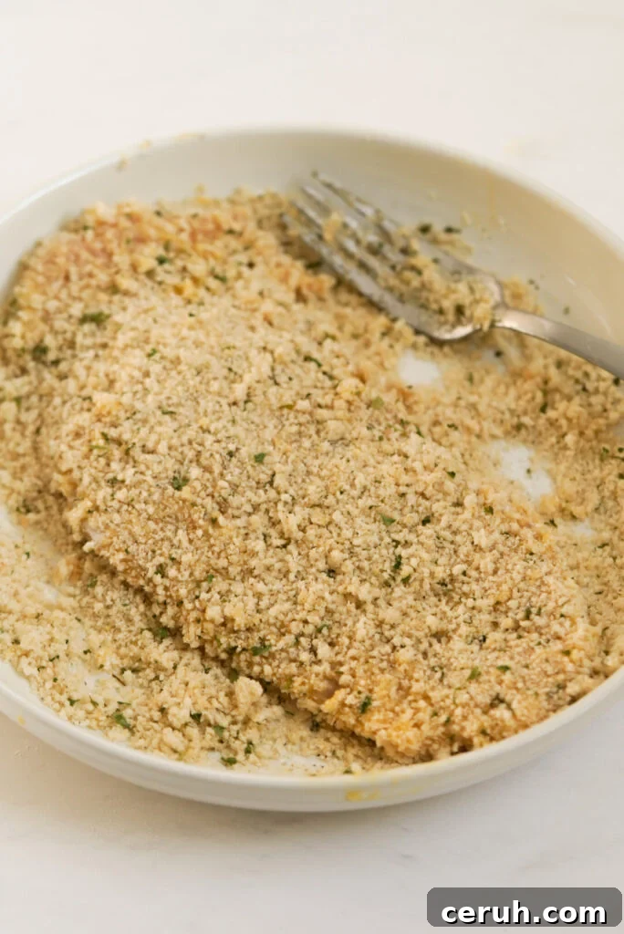 process shot - pounded chicken cutlet getting tossed in the breadcrumb mixture.