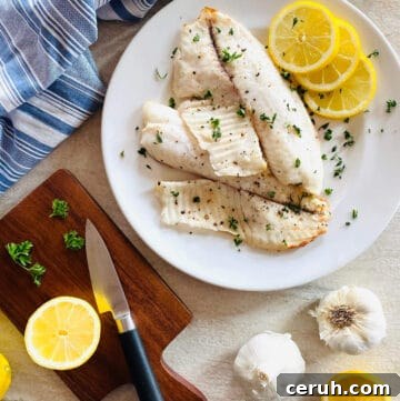 air fryer tilapia on a plate with lemon and parsley
