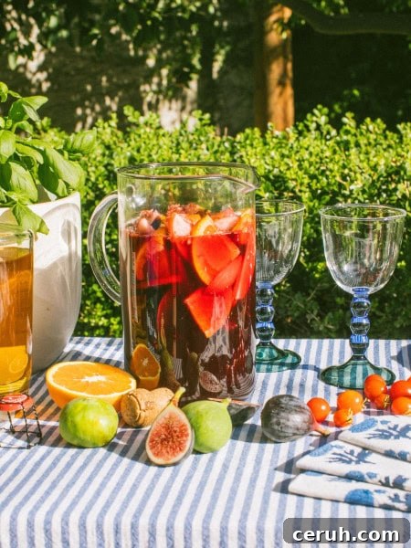 a large pitcher full of sangria with figs, oranges, and other fruits scattered around