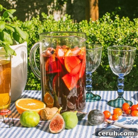 a large pitcher full of sangria with figs, oranges, and other fruits scattered around