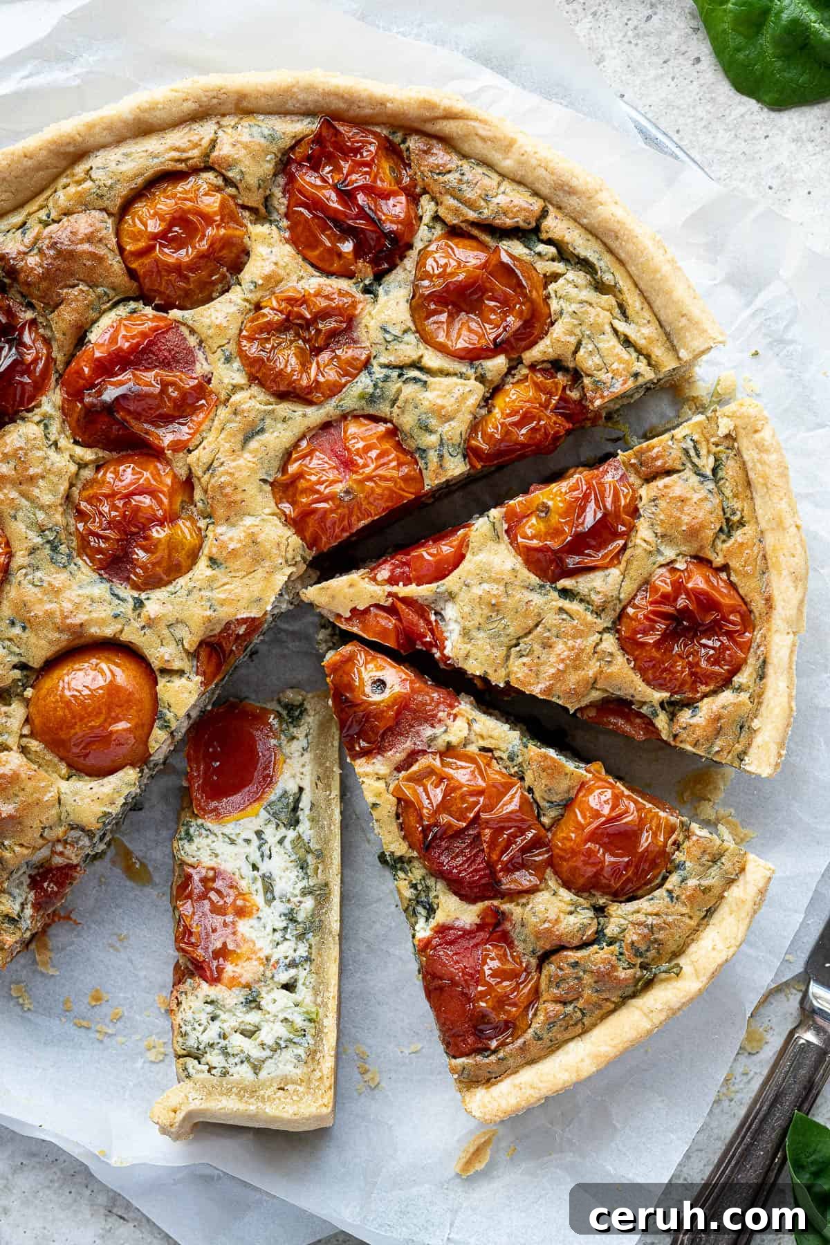 Close up of the sliced vegan tomato spinach quiche, one slice on it's side.