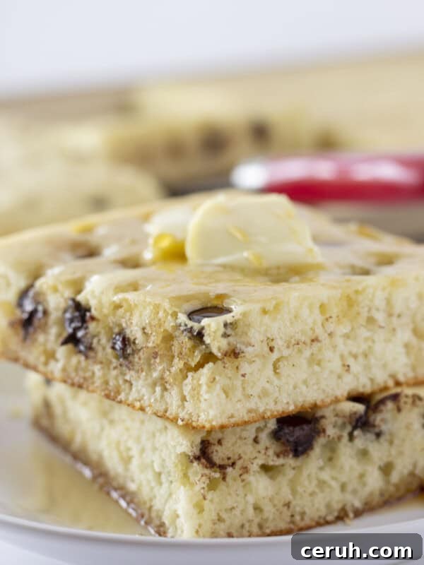 A serving of sheet pan pancakes with chocolate chips and syrup.
