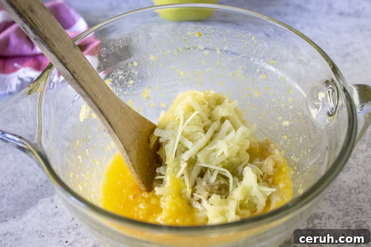 Eggs, butter and sugar combined together with grated apples on top of mixture.