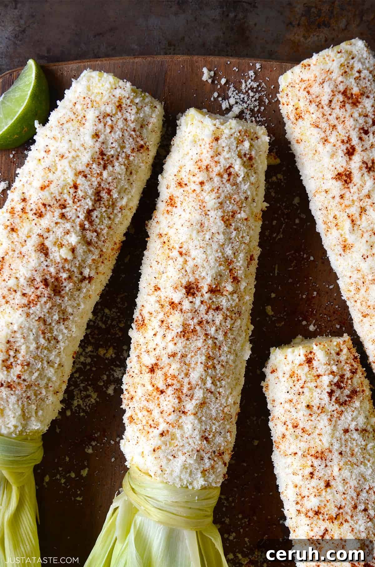 Mexican street corn (elote) slathered in creamy sauce, coated in crumbled Cotija cheese, and sprinkled with chili powder.