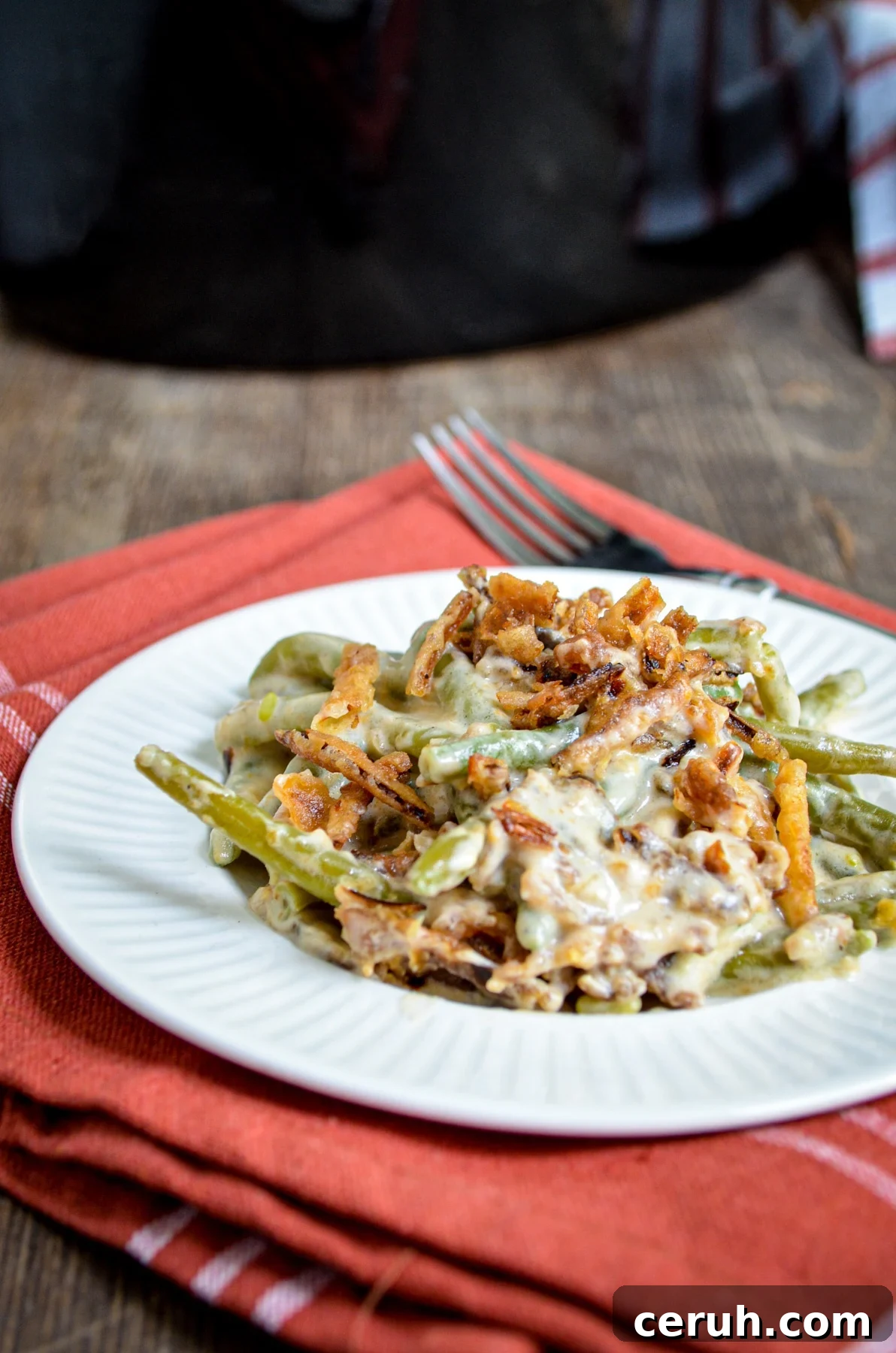Creamy Slow Cooker Green Bean Casserole for Holidays 2 A serving of green bean casserole, with a slow cooker in the background.