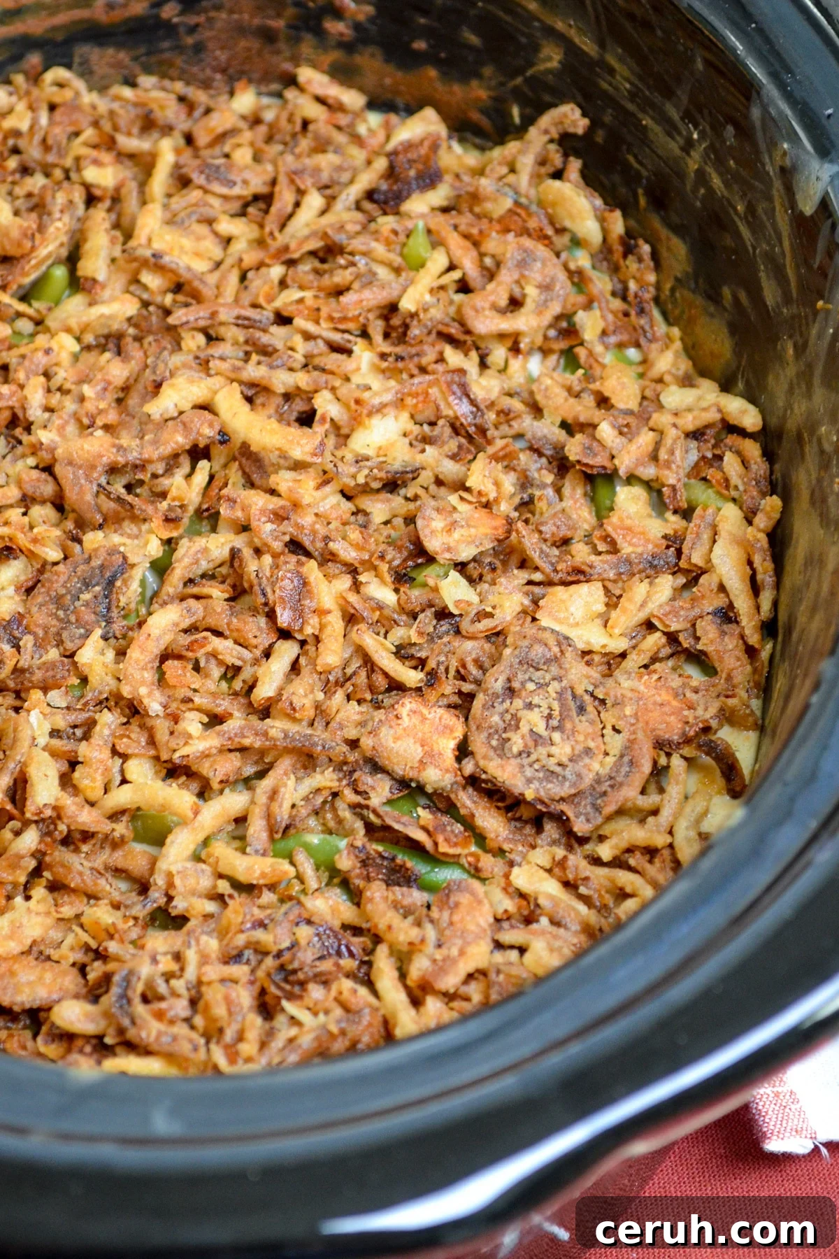Creamy Slow Cooker Green Bean Casserole for Holidays 7 A slow cooker full of green bean casserole, topped with french fried onions.