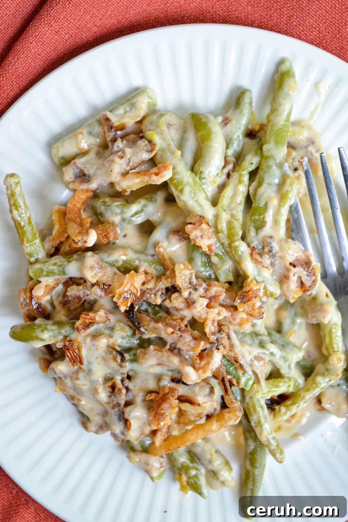 Creamy Slow Cooker Green Bean Casserole for Holidays 9 A plate of green bean casserole, topped with french fried onions.