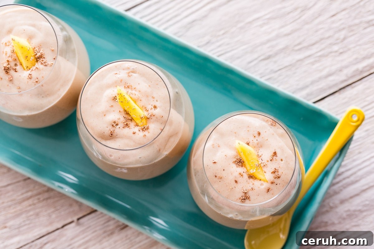 Closeup of a coconut mango smoothie in a glass garnished with mango.
