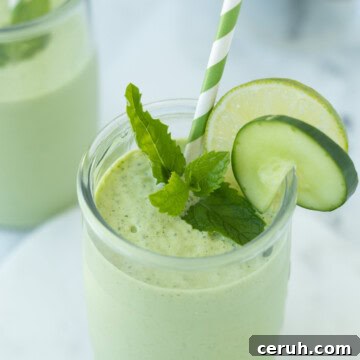 Creamy light green cucumber mint smoothie in a glass with lime slice.
