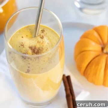 Creamy orange pumpkin pie smoothie in a glass with a silver straw.