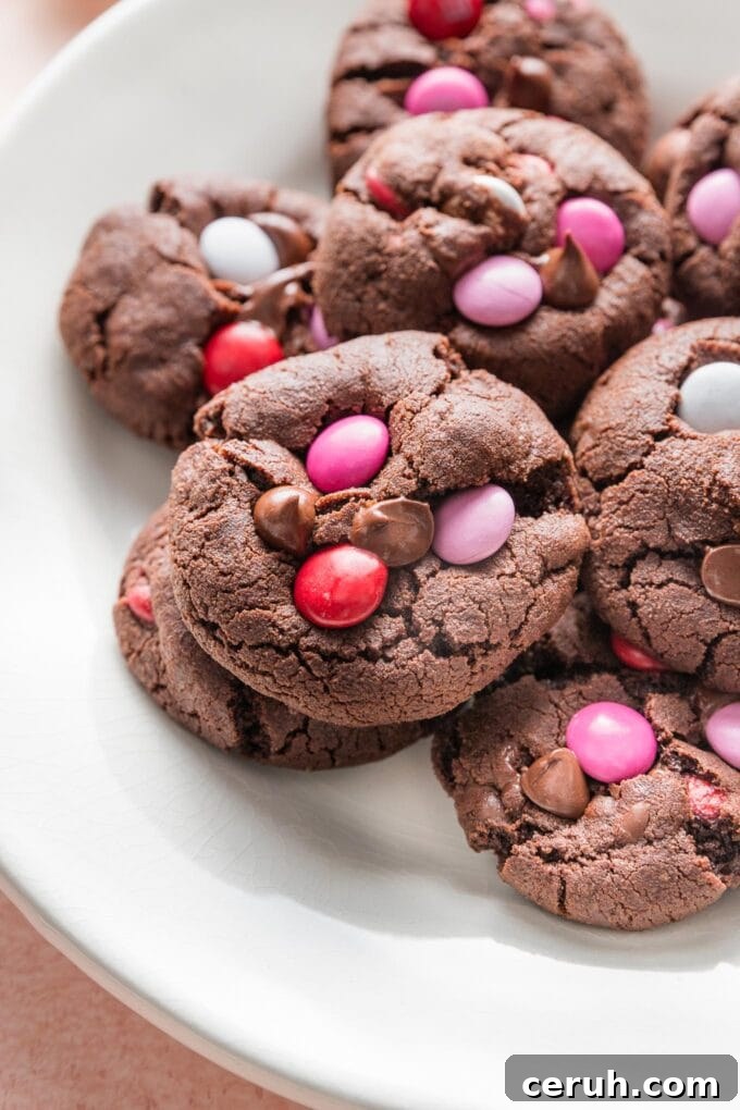 Close up of a double chocolate cookie with chocolate chips and Valentines-themed M&Ms.