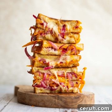 6 sandwich halves stacked on each other on small wooden board