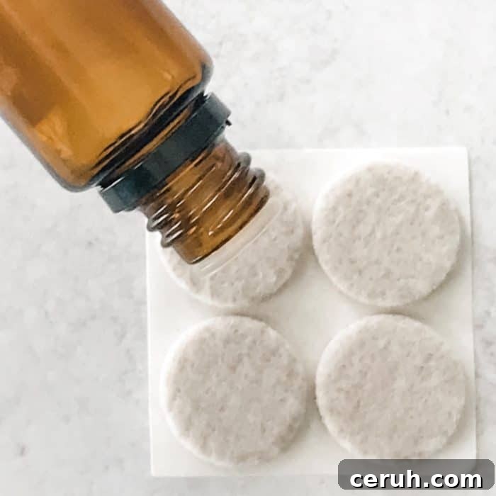 adding drops of essential oil from essential oil bottle to felt pads