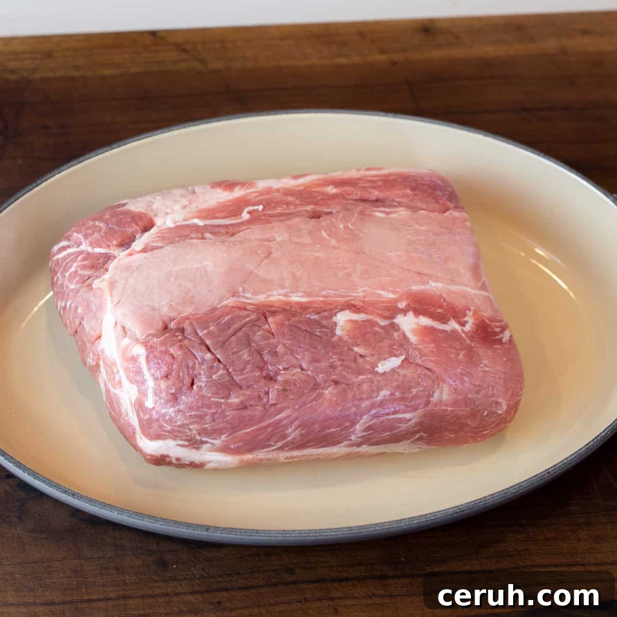 Raw pork roast in a roasting dish.