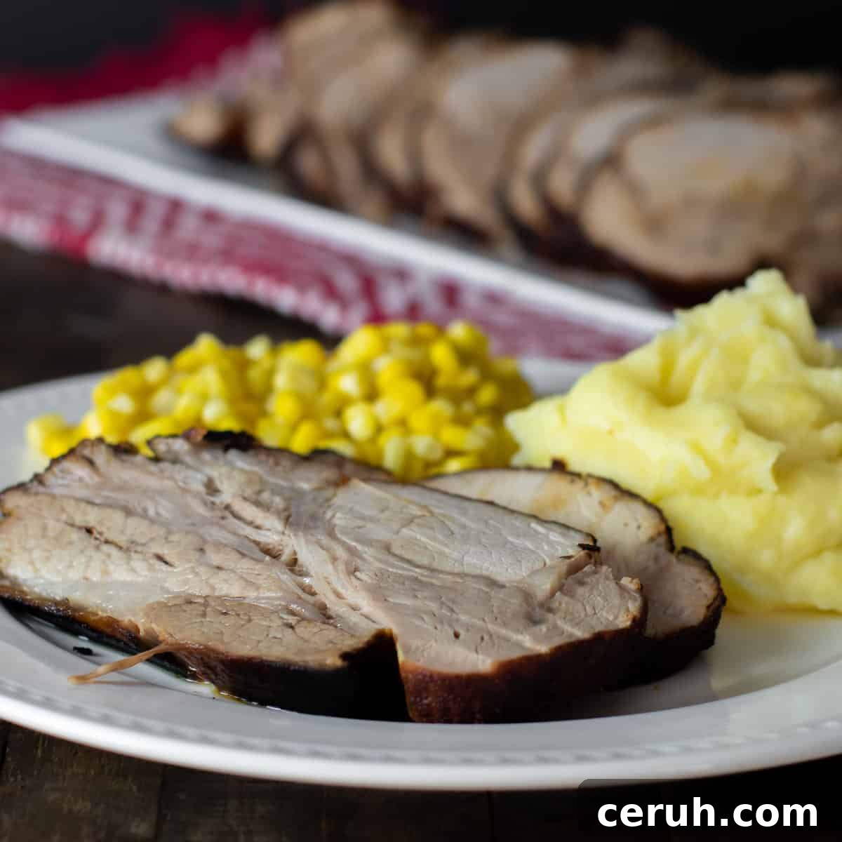 Close up picture of a dinner plate with pork roast, mashed potatoes and corn.