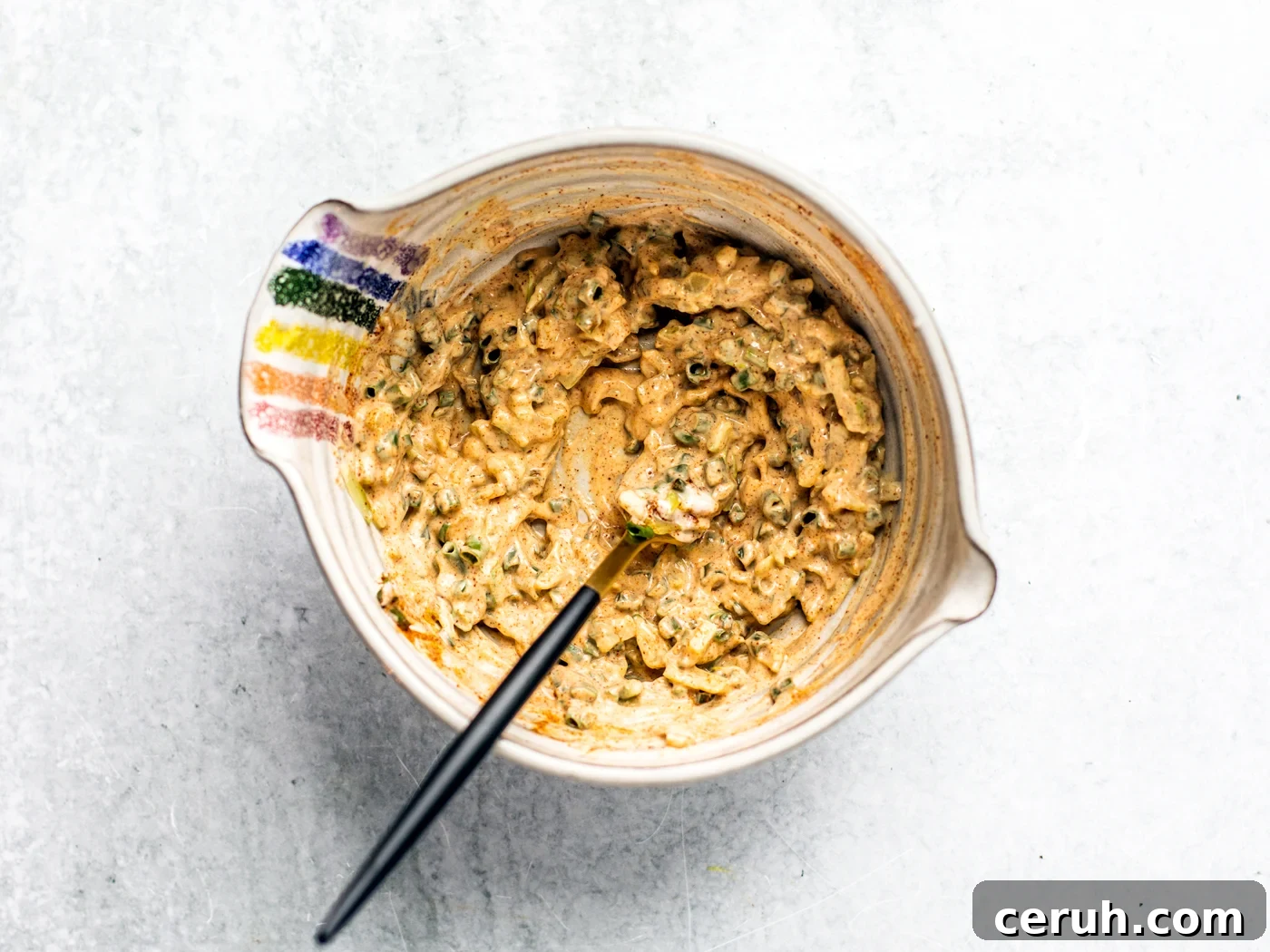 Mixing bowl full of fully blended mayo, chives, celery, and spices.