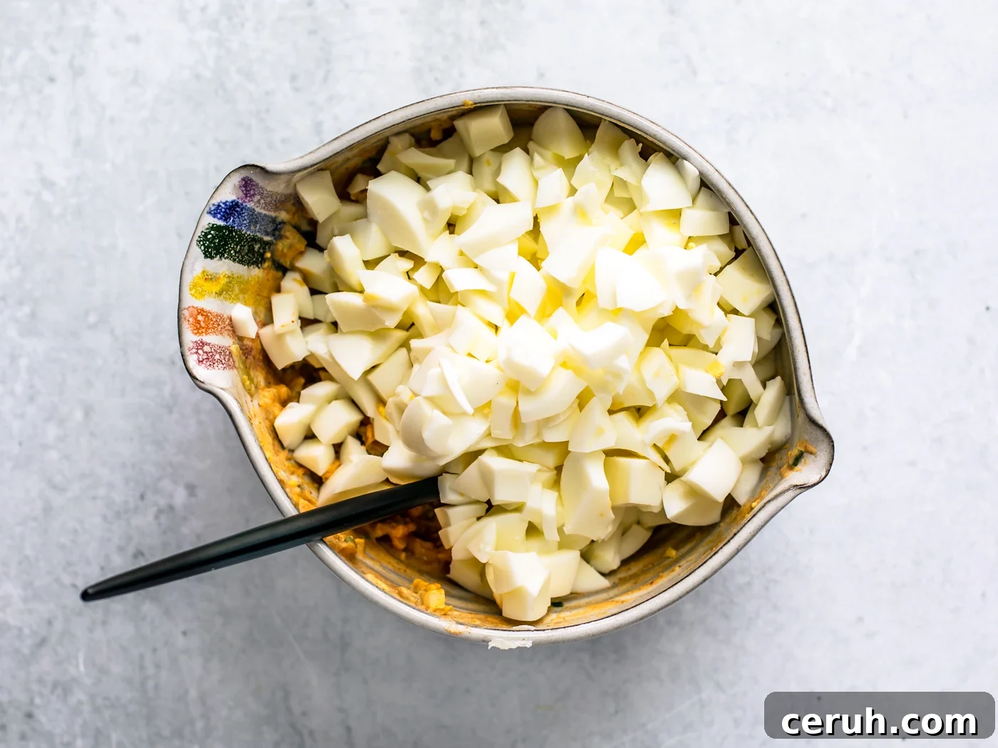 Mixing bowl full of mayo mixture and roughly chopped egg whites.