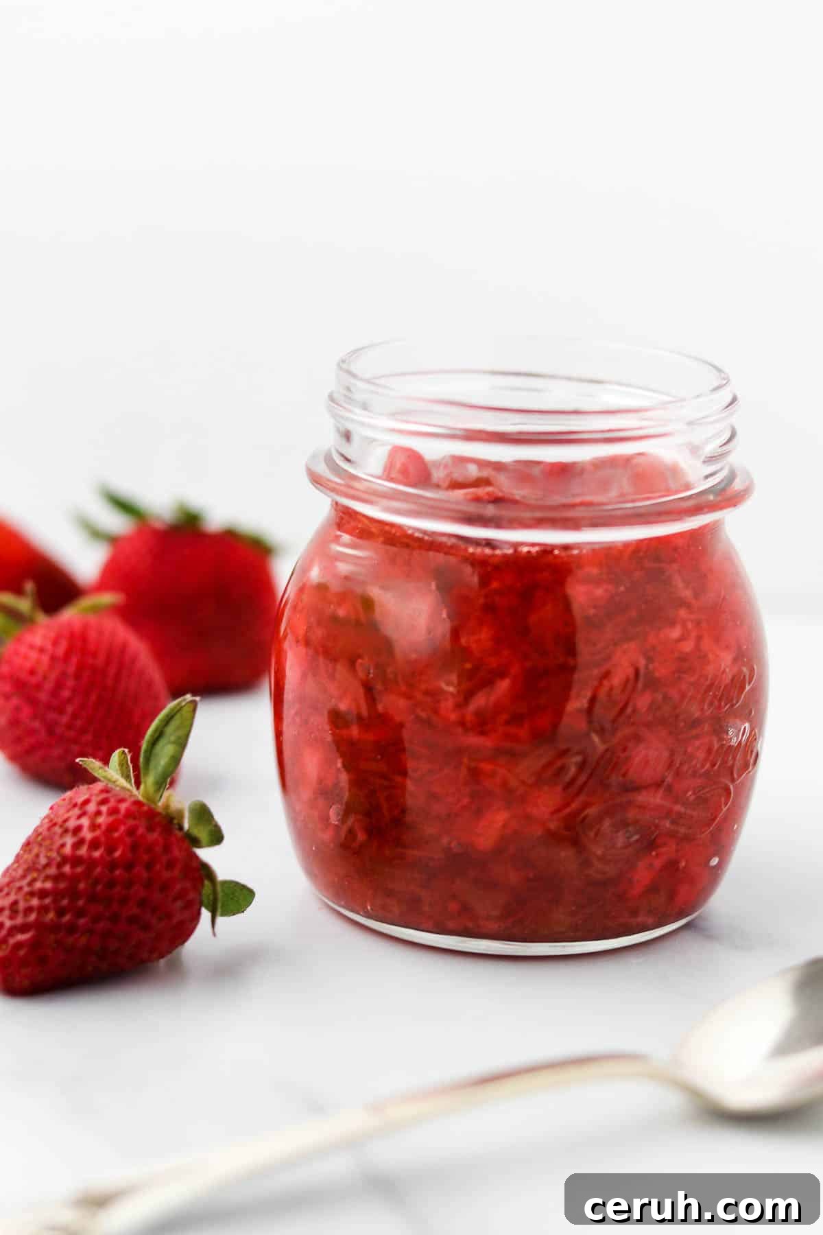 Strawberry Rhubarb Compote Recipe: Quick Homemade Fruit Sauce 2 Strawberry Rhubarb Compote in a jar next to a spoon and strawberries.