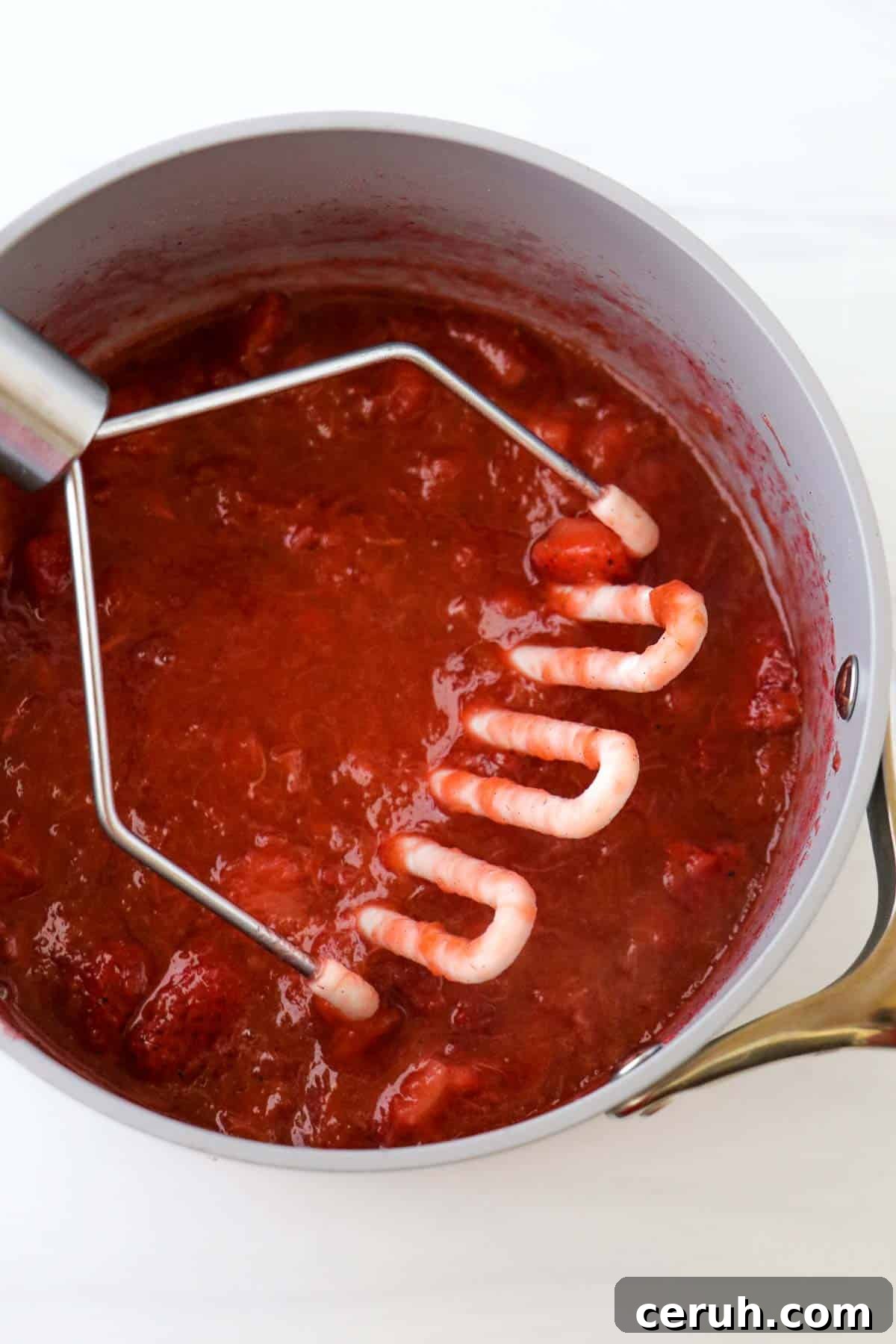 Strawberry Rhubarb Compote Recipe: Quick Homemade Fruit Sauce 7 Potato masher in a saucepan with Strawberry Rhubarb Compote.