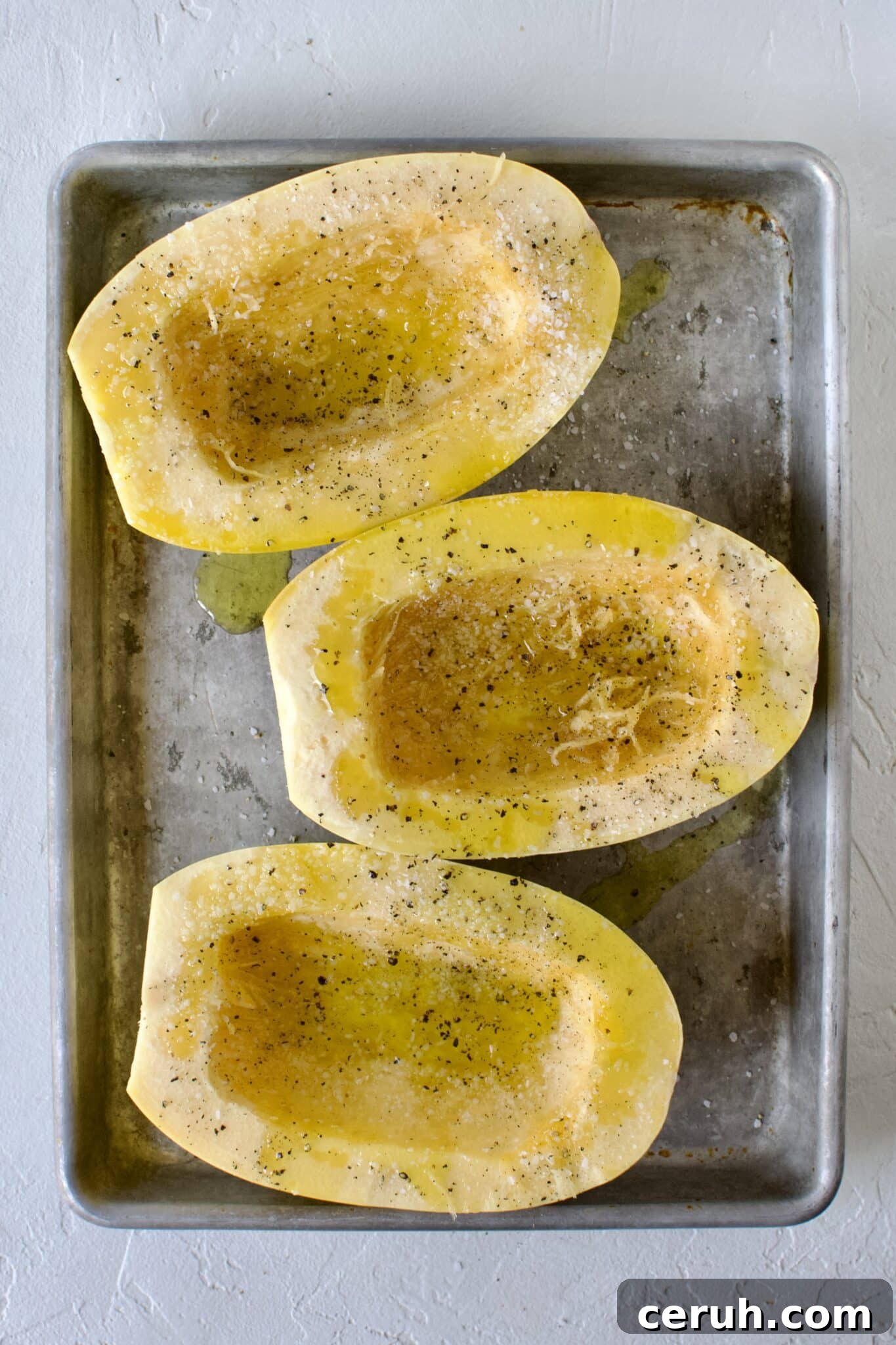 Spaghetti Squash, cut side up, seeds removed, placed on a sheet pan and seasoned with olive oil, salt, and pepper.