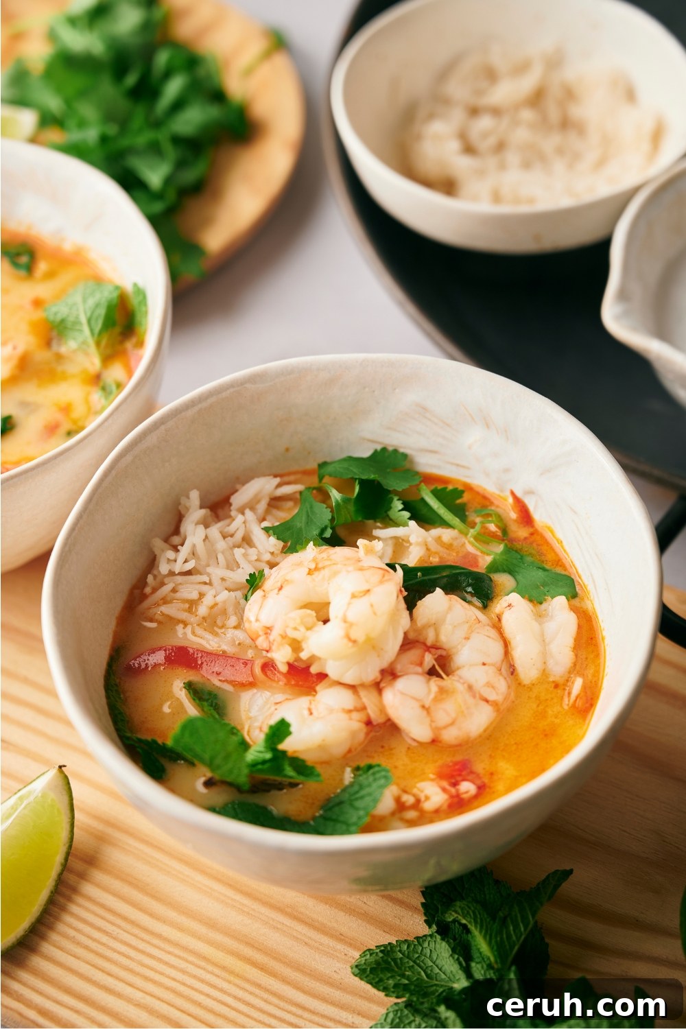 Shrimp on top of a soup in a white bowl.