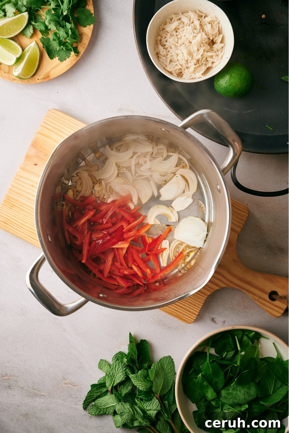 Sliced red bell peppers and onions cooking in a pot.