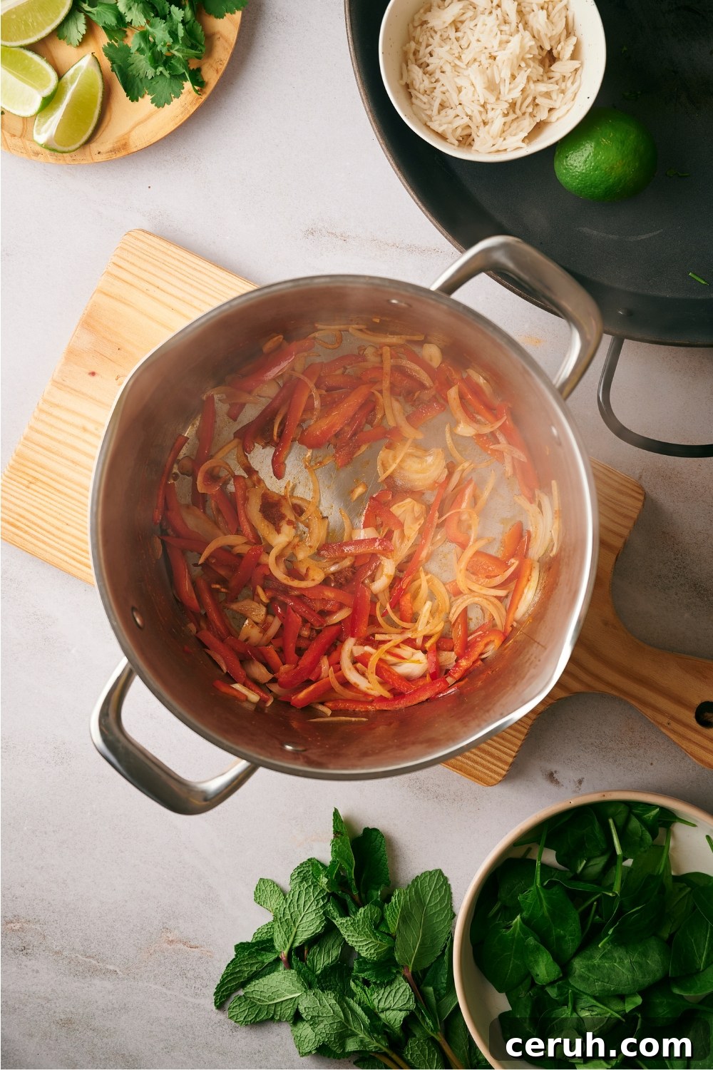 Cooked sliced red bell peppers and onions in a pot.