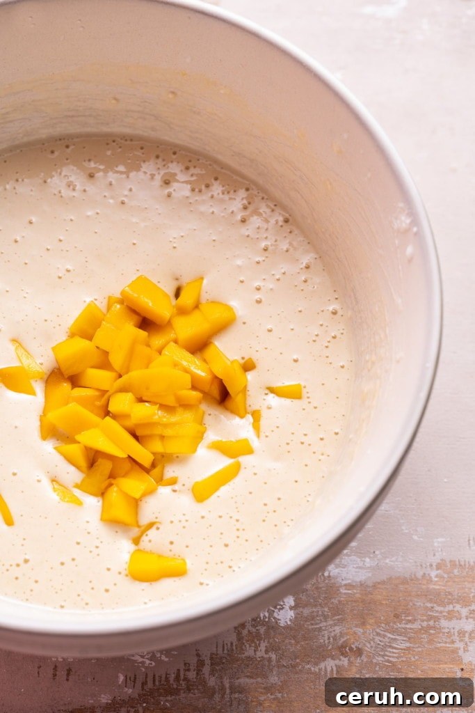 Folding in diced mango into pancake batter