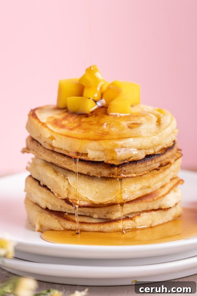 Close up of mango pancakes with syrup dripping down off the sides of the stack