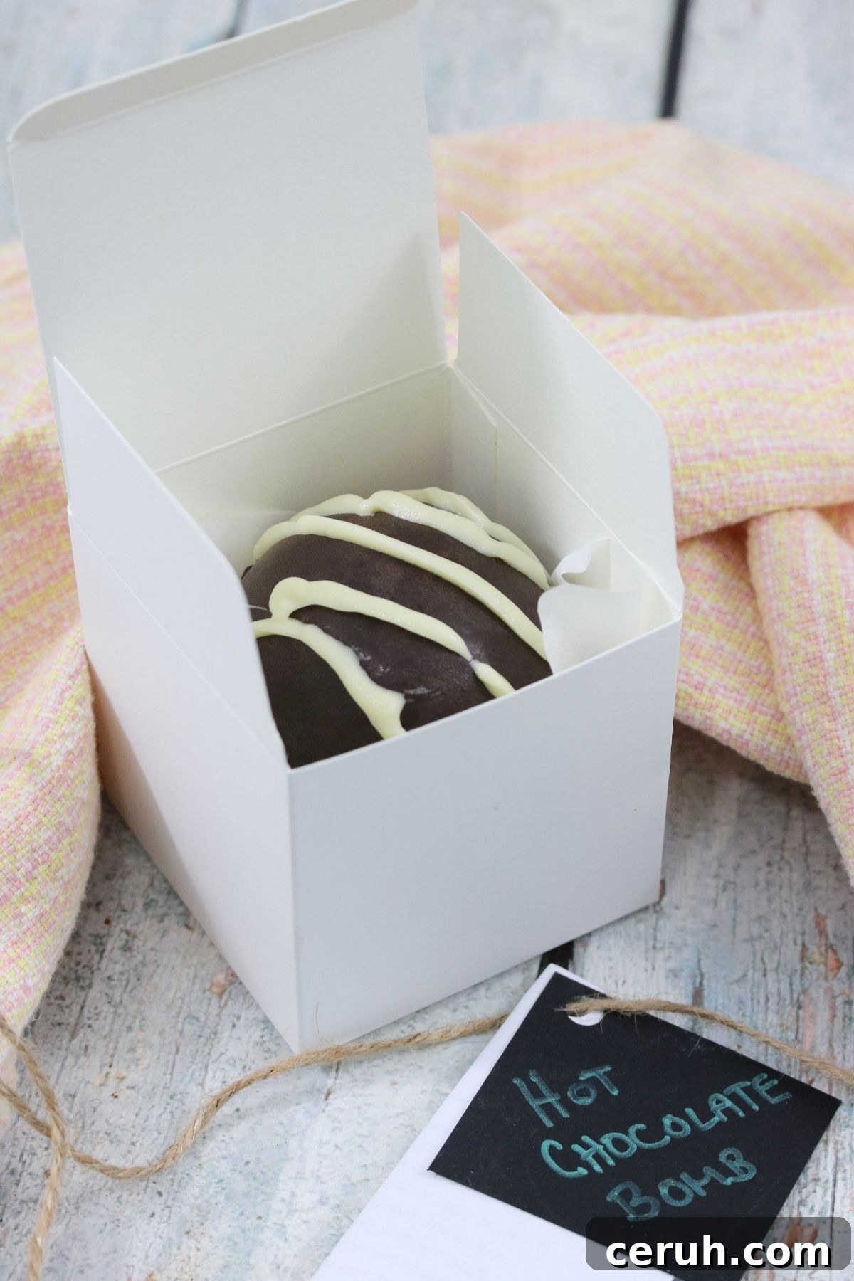 Hot chocolate bomb with white drizzle in a white box as a gift.