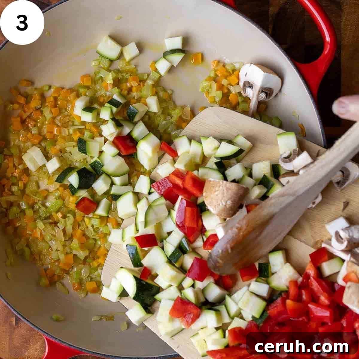 Adding chopped mix of vegetables to a pan of cooked chopped onion, carrot and celery.