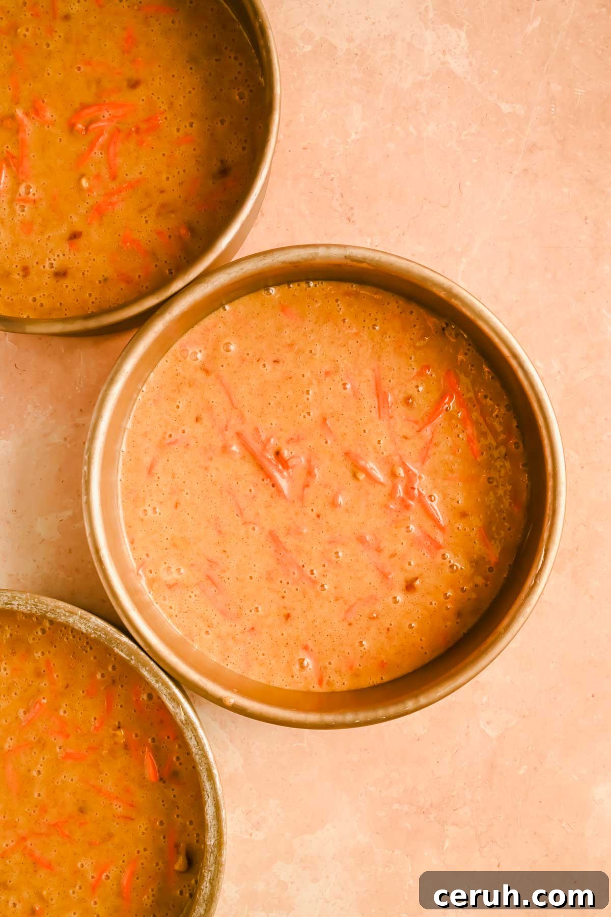 three carrot cakes in circular pans, unbaked.