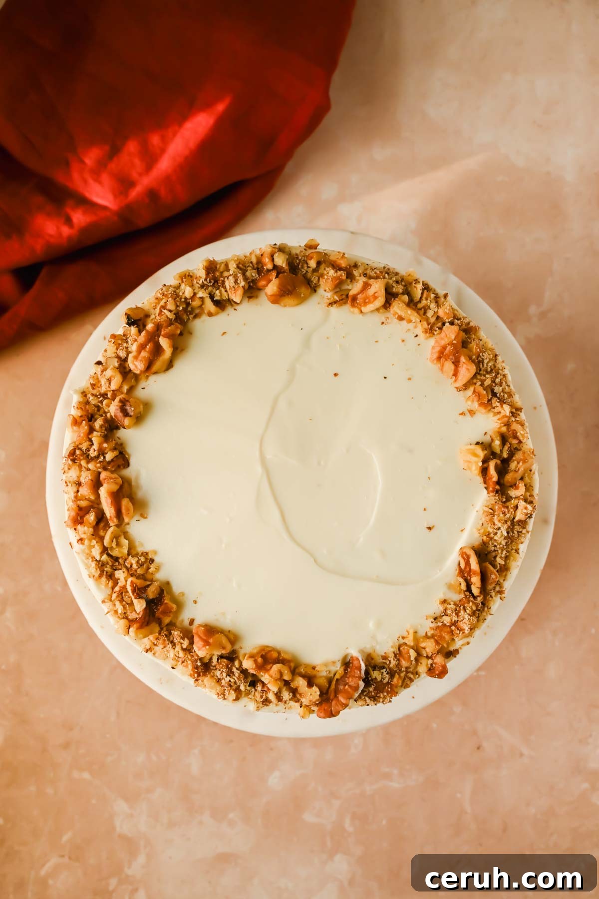 frosted carrot cake garnished with walnut pieces.